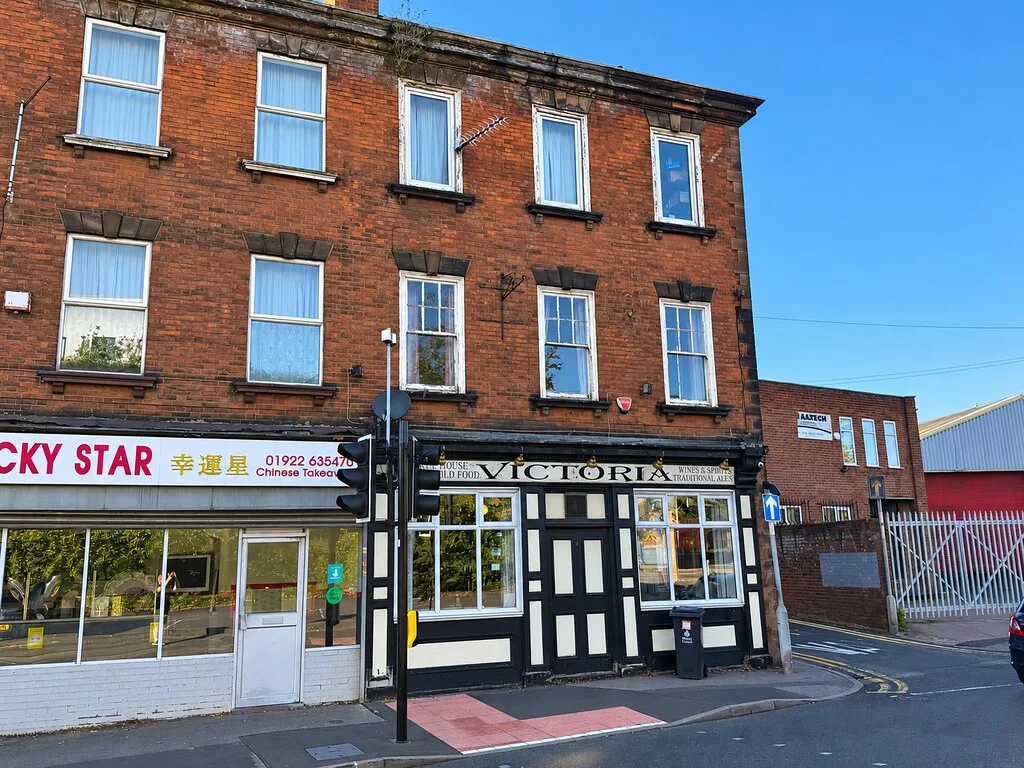 The Victoria in Walsall, a three-storey red-brick corner building with a black and white ground-floor frontage
