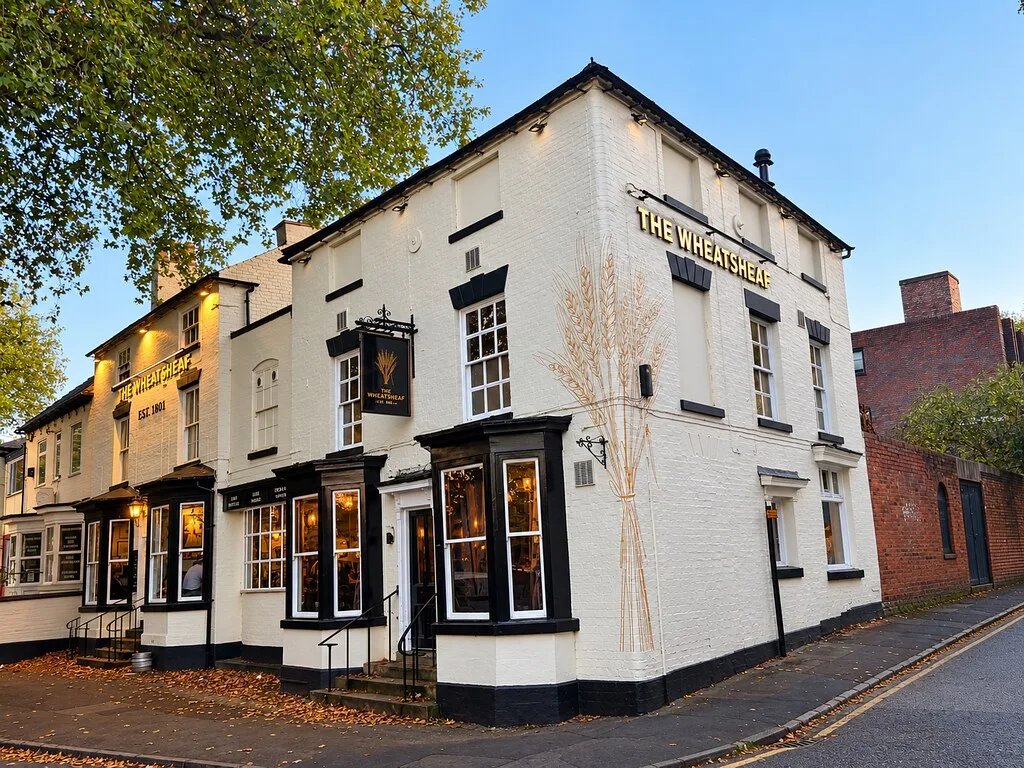The Wheatsheaf in Walsall, a white-painted corner pub with black window frames and lit bay windows