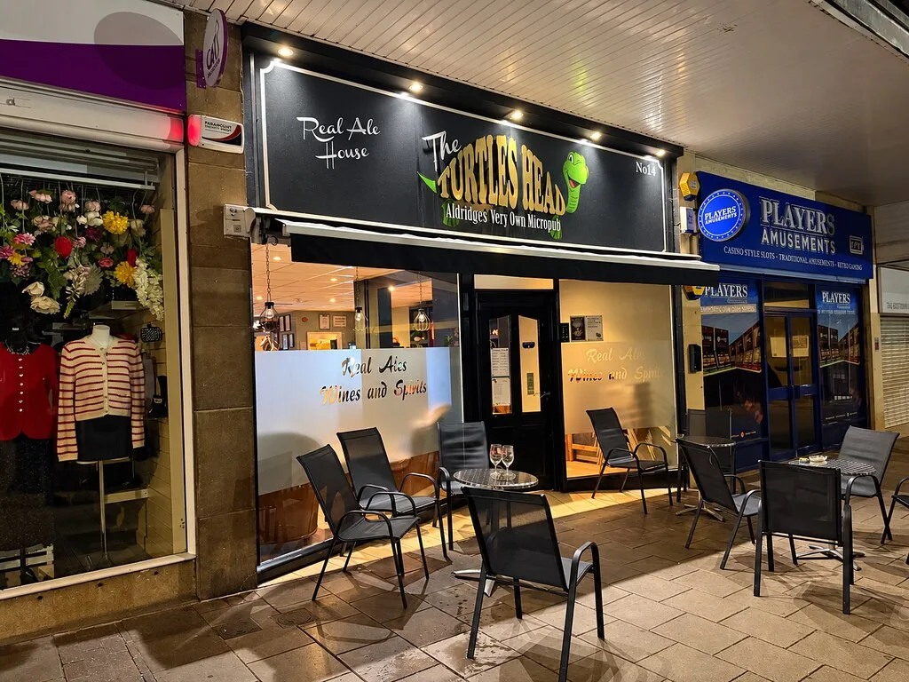 The Turtles Head micropub in Aldridge, a shopfront under a parade canopy with tables and chairs outside