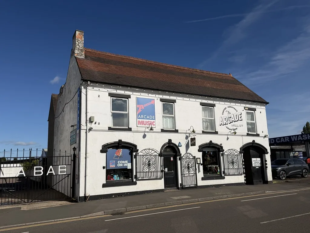 Arcade in Cannock, a white-painted two-storey pub with black window frames and arched ironwork over the windows