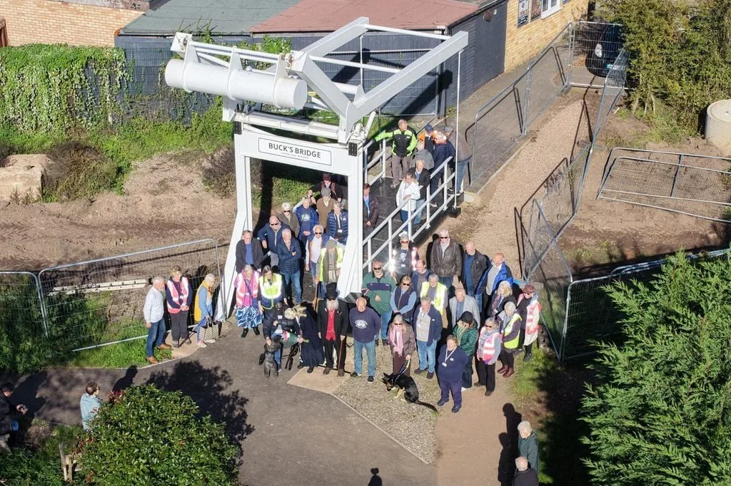 Aerial view of a large group of volunteers and supporters standing on and in front of the white Buck's Bridge lift bridge at Gallows Reach, Lichfield