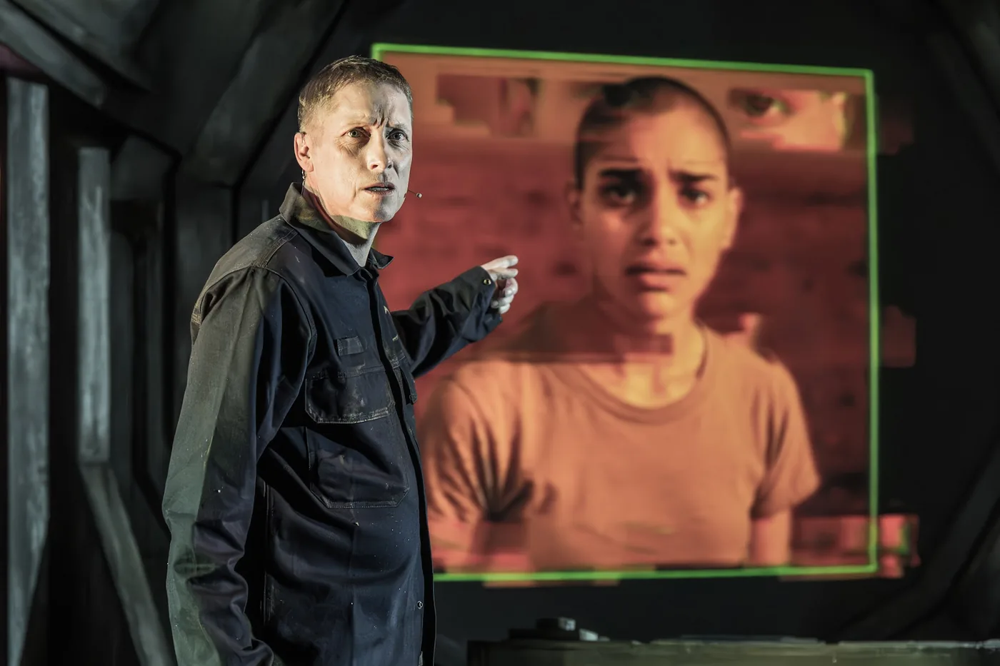 A performer on stage in front of a projected face in The Void